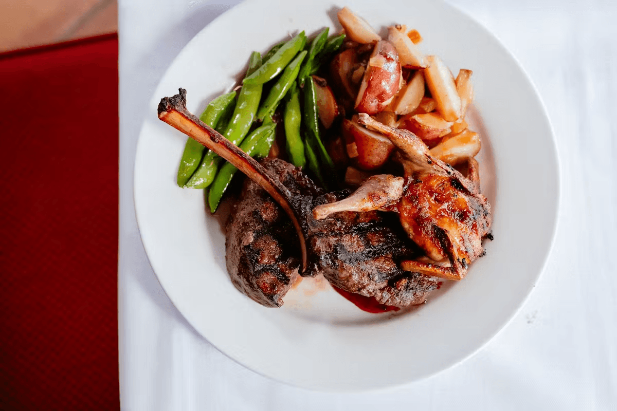 A plate featuring grilled lamb chops, green beans, and roasted potatoes.