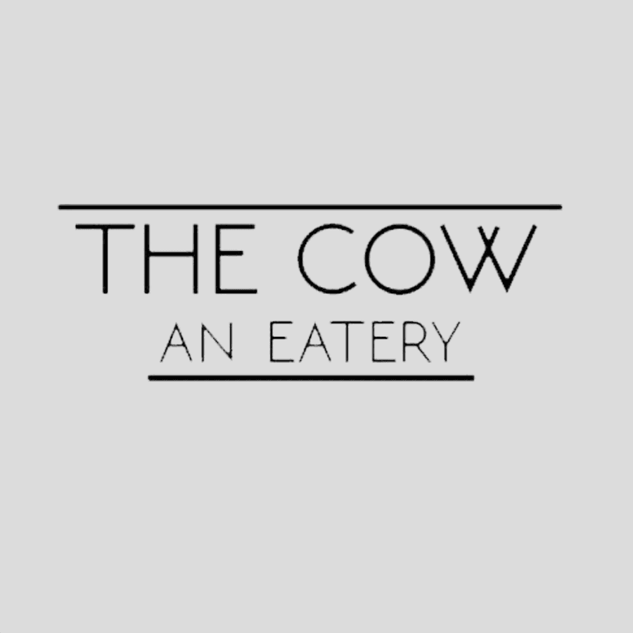 Black text logo for The Cow: An Eatery on a light gray square background.