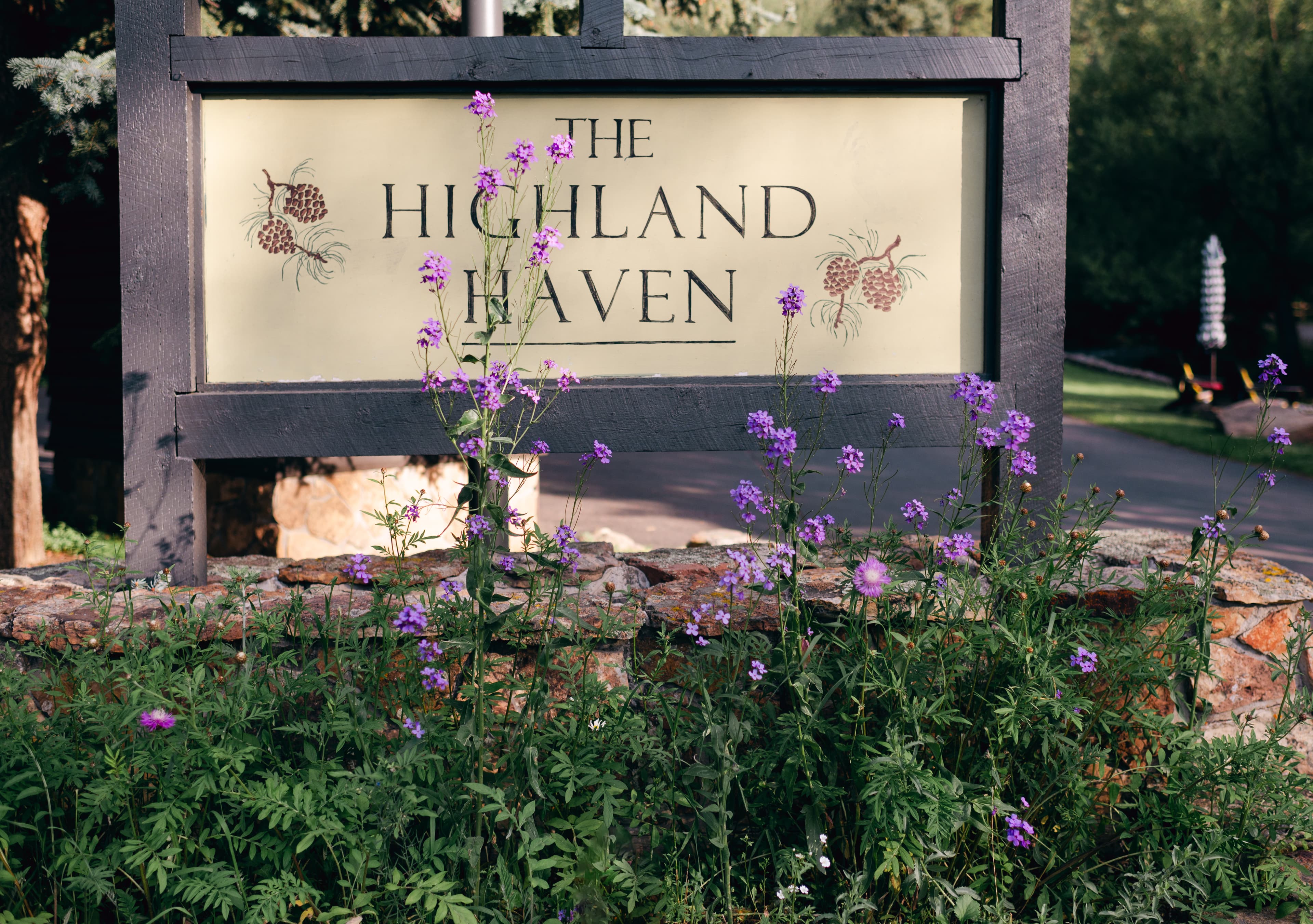 A sign reading "The Highland Haven" surrounded by purple wildflowers.