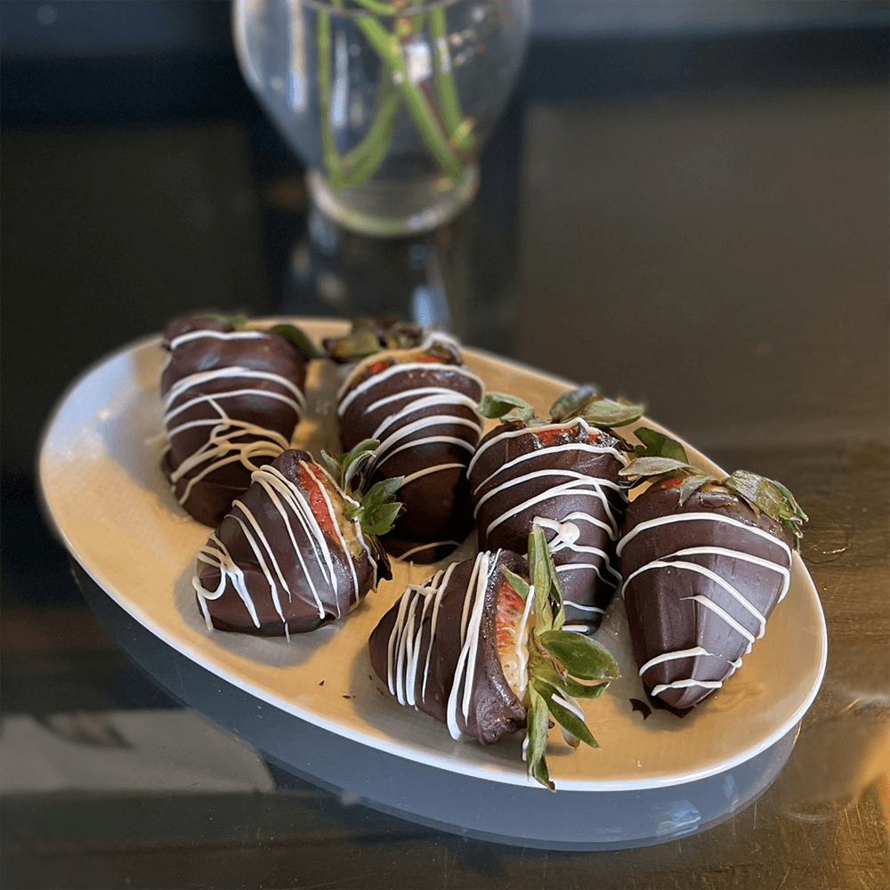 A plate of chocolate-covered strawberries drizzled with white chocolate.