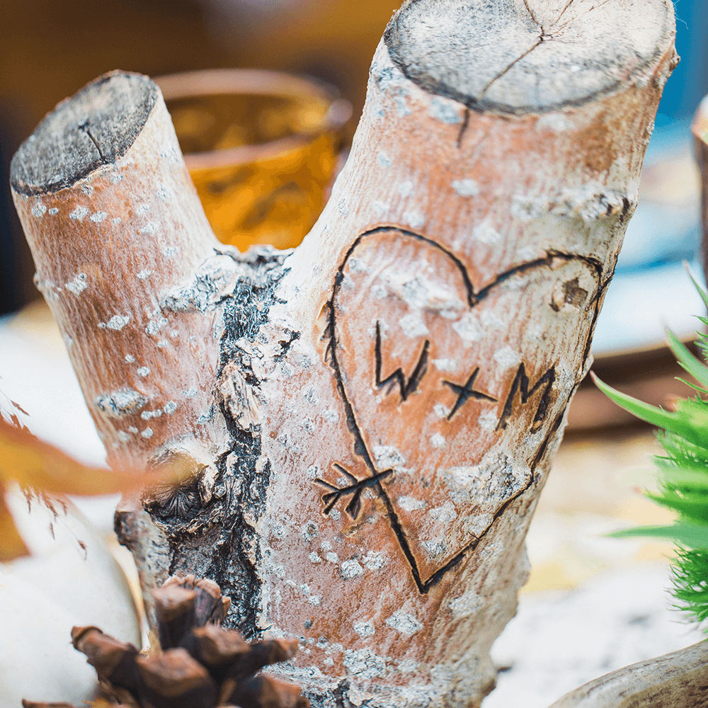 A heart carved into a piece of wood shows the initials "W + M."