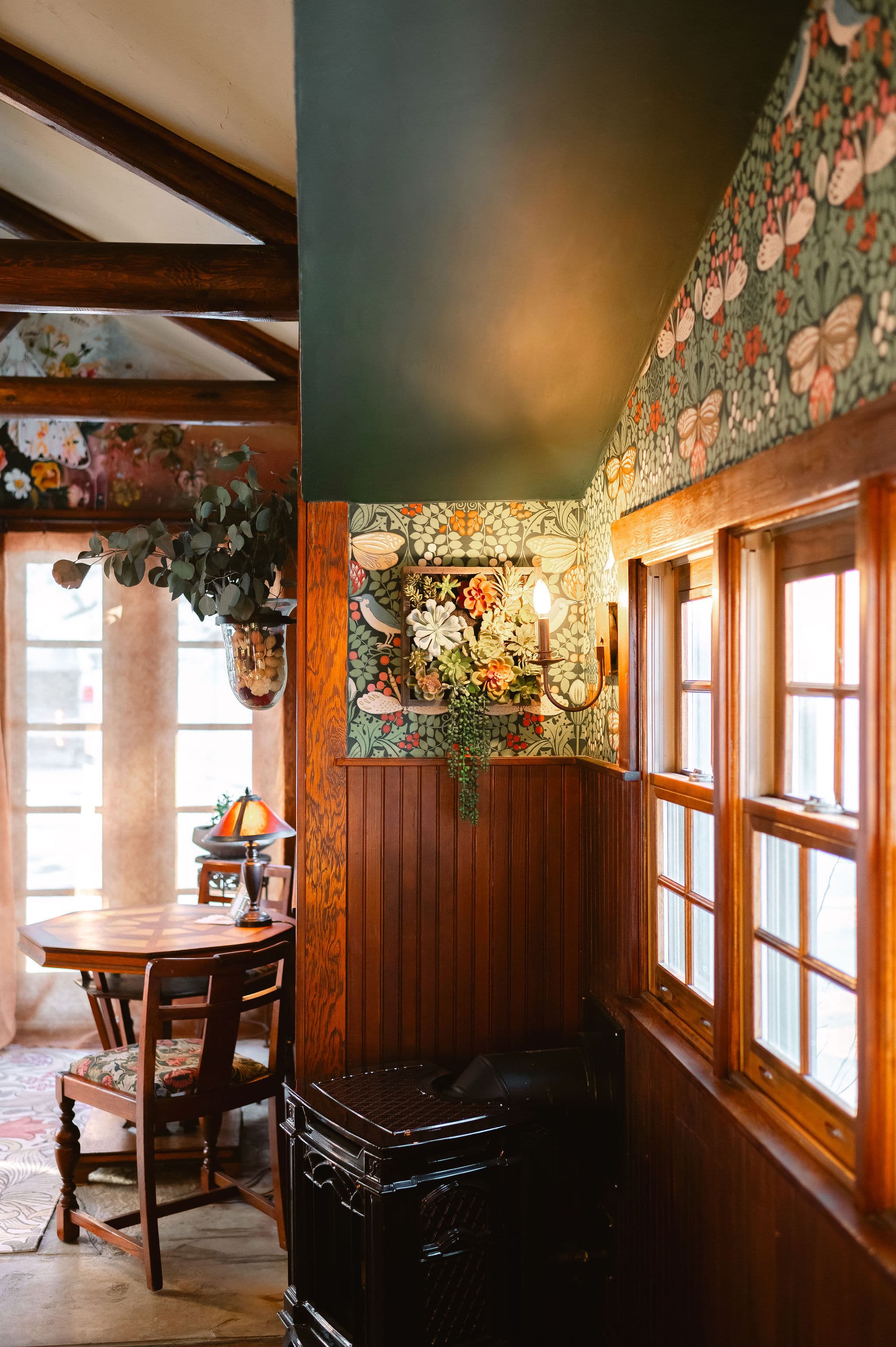 Cozy interior corner featuring floral wallpaper, wooden accents, and a small dining table.
