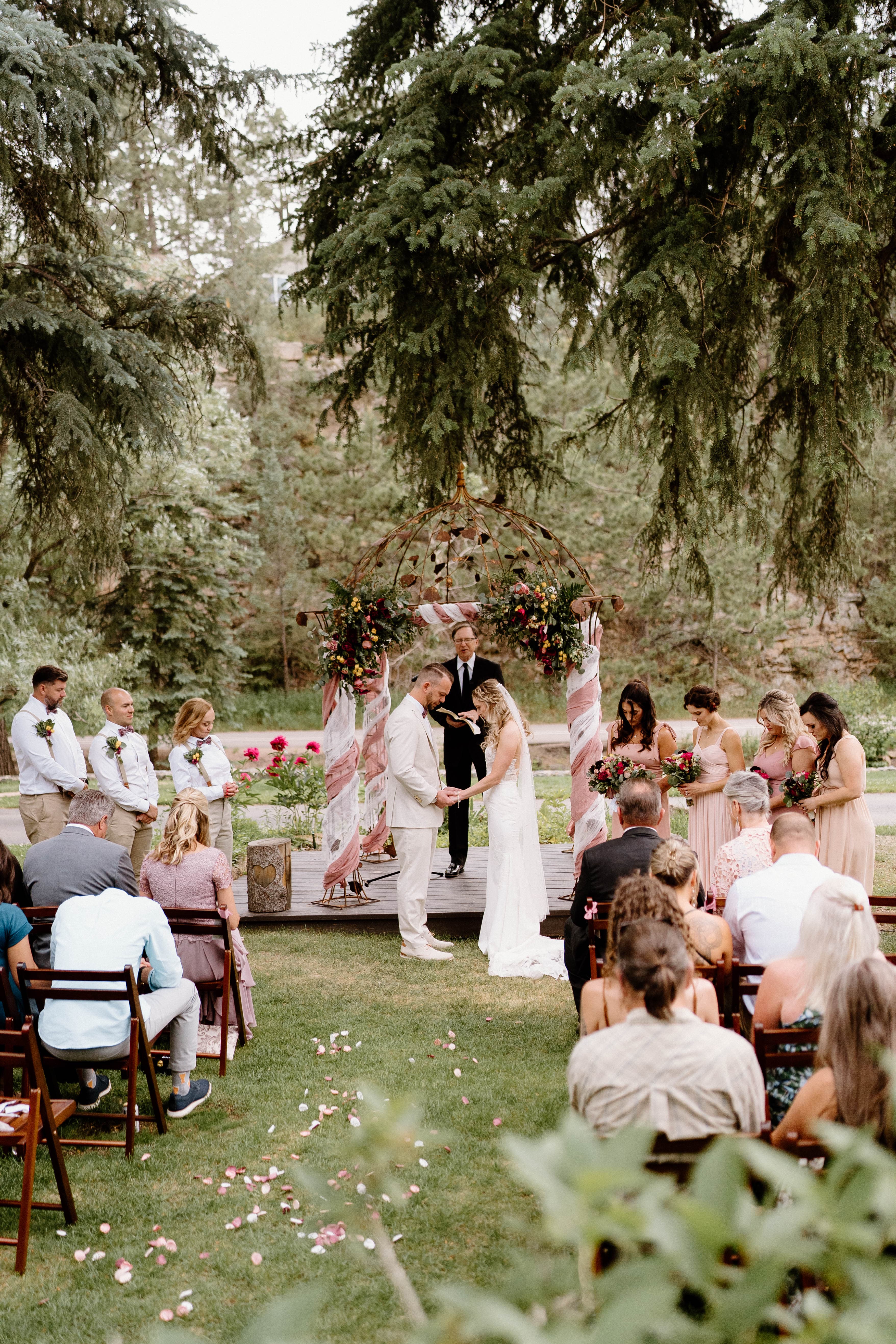A couple exchanges vows during an outdoor wedding ceremony surrounded by family and friends.
