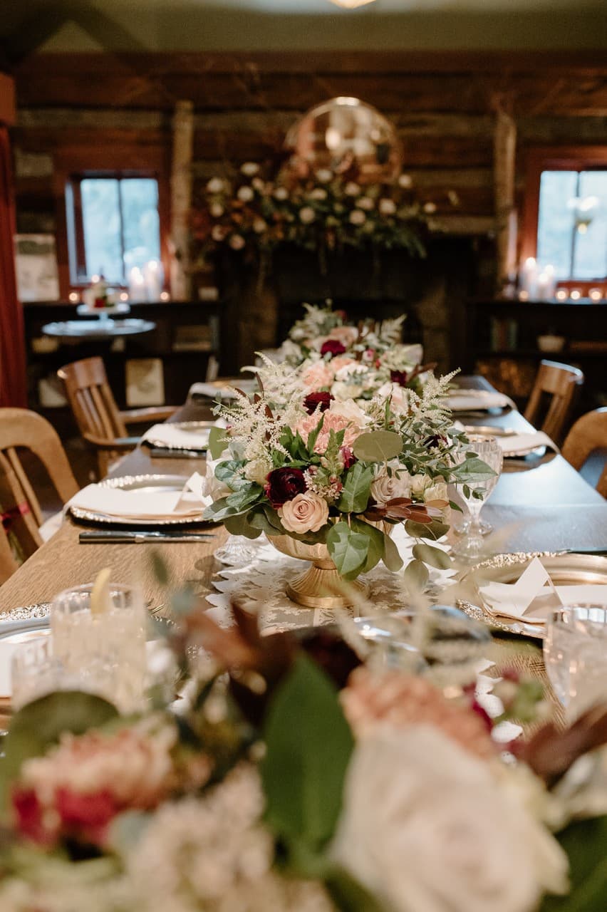 A beautifully set dining table adorned with floral arrangements in a rustic interior.